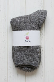 Pair of gray socks with a white label on a light wooden background