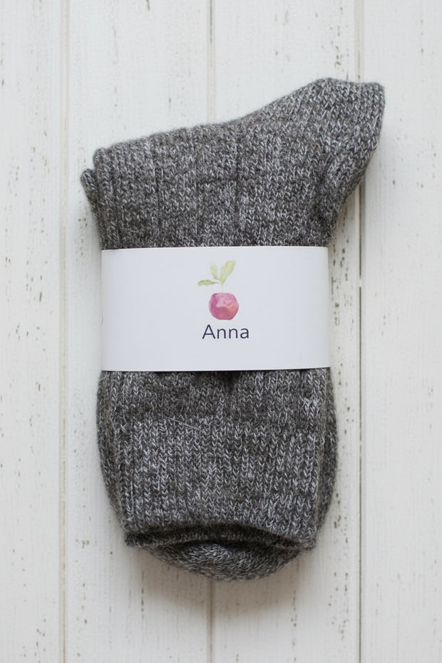 Pair of gray socks with a white label on a light wooden background