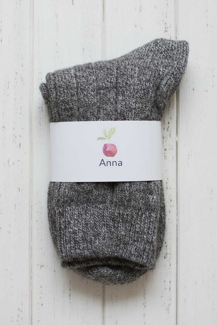 Pair of gray socks with a white label on a light wooden background