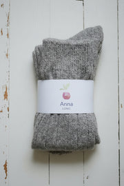 Pair of gray socks with a 'Anna' label on a wooden surface