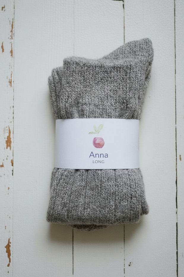 Pair of gray socks with a 'Anna' label on a wooden surface