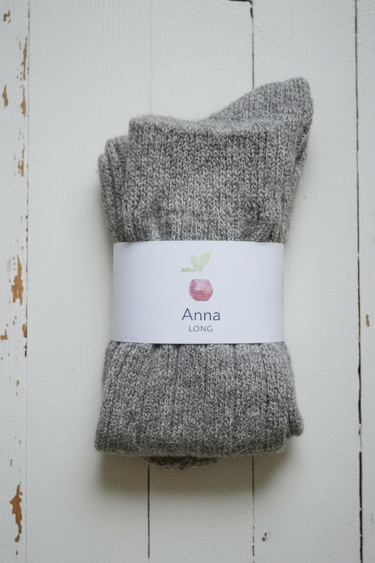 Pair of gray socks with a 'Anna' label on a wooden surface