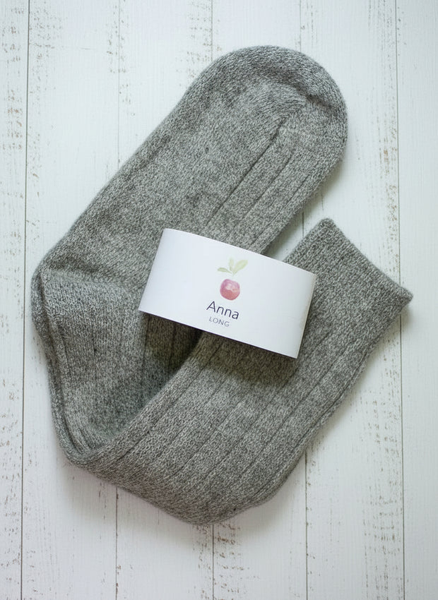 Pair of gray socks with a visible brand label on a light wooden surface