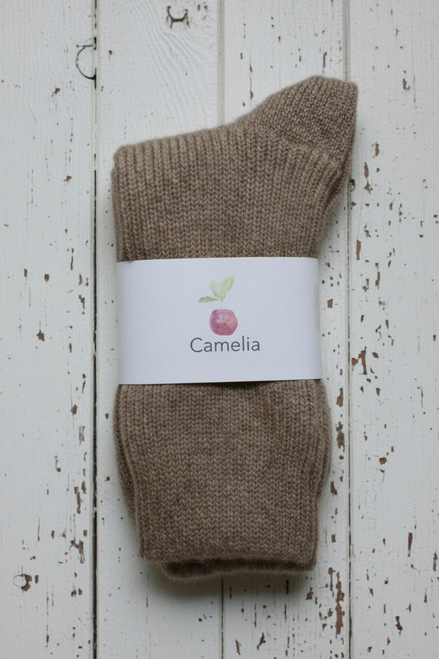 Brown sock with a 'Camelia' label on a wooden surface