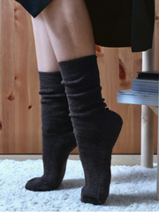 Person wearing brown socks with a wooden background on a white carpet