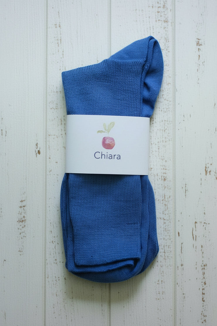 Pair of blue socks with a white label on a wooden surface