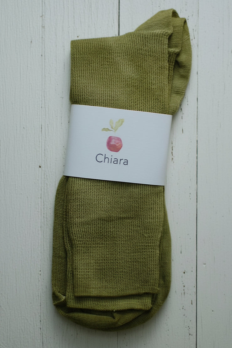Green sock with a Chiara label on a white wooden surface