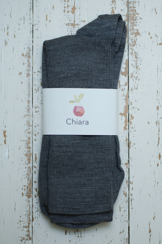 Pair of dark gray socks with a white label on a wooden surface