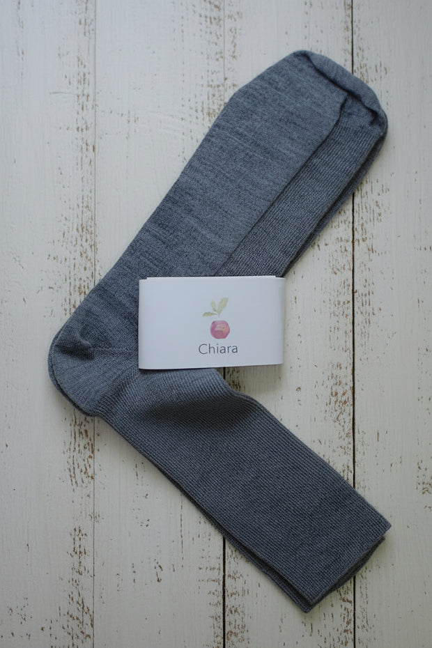 Grey sock with a white card displaying 'Chiara' on a wooden surface
