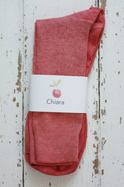 Reddish pink socks with a 'Chiara' label on a wooden surface