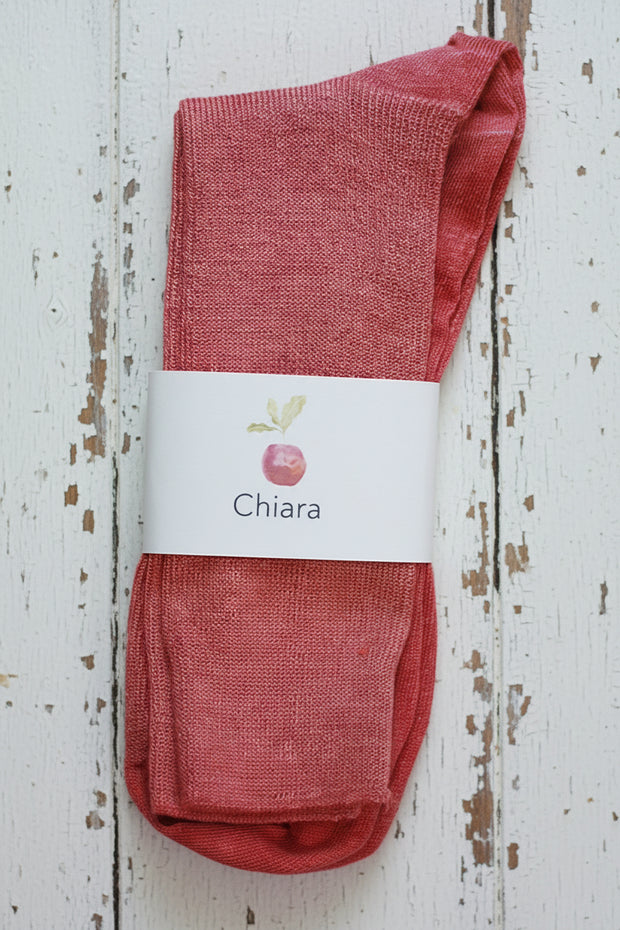 Reddish pink socks with a 'Chiara' label on a wooden surface