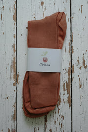 Pair of orange socks with a 'Chiara' label on a light wooden background