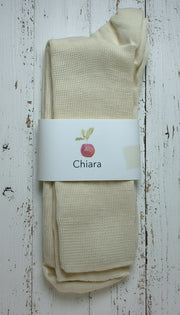 Off white wool socks with a 'Chiara' label on a white wooden background
