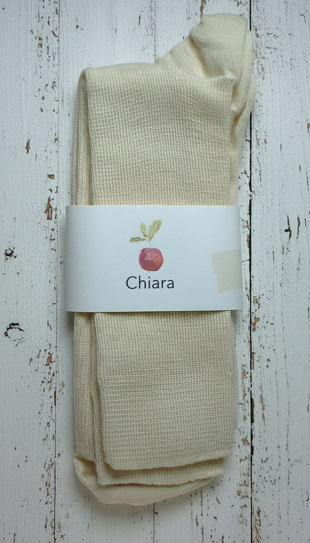 Off white wool socks with a 'Chiara' label on a white wooden background