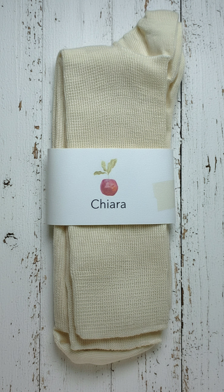 Off white wool socks with a 'Chiara' label on a white wooden background
