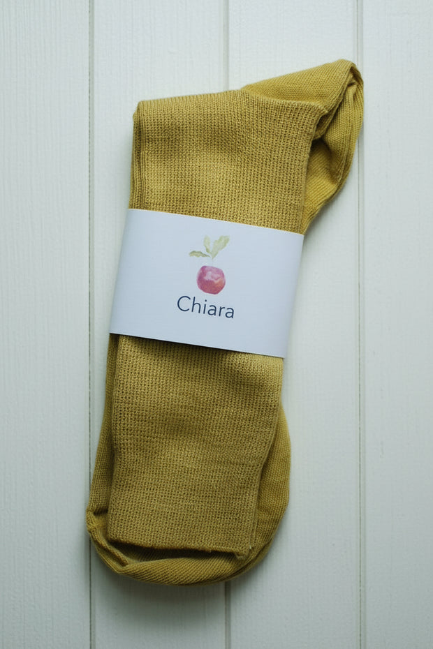 Mustard yellow socks with a 'Chiara' label on a white wooden background