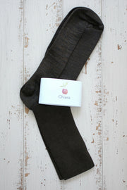 Dark brown ankle sock with a white label on a rustic wooden surface