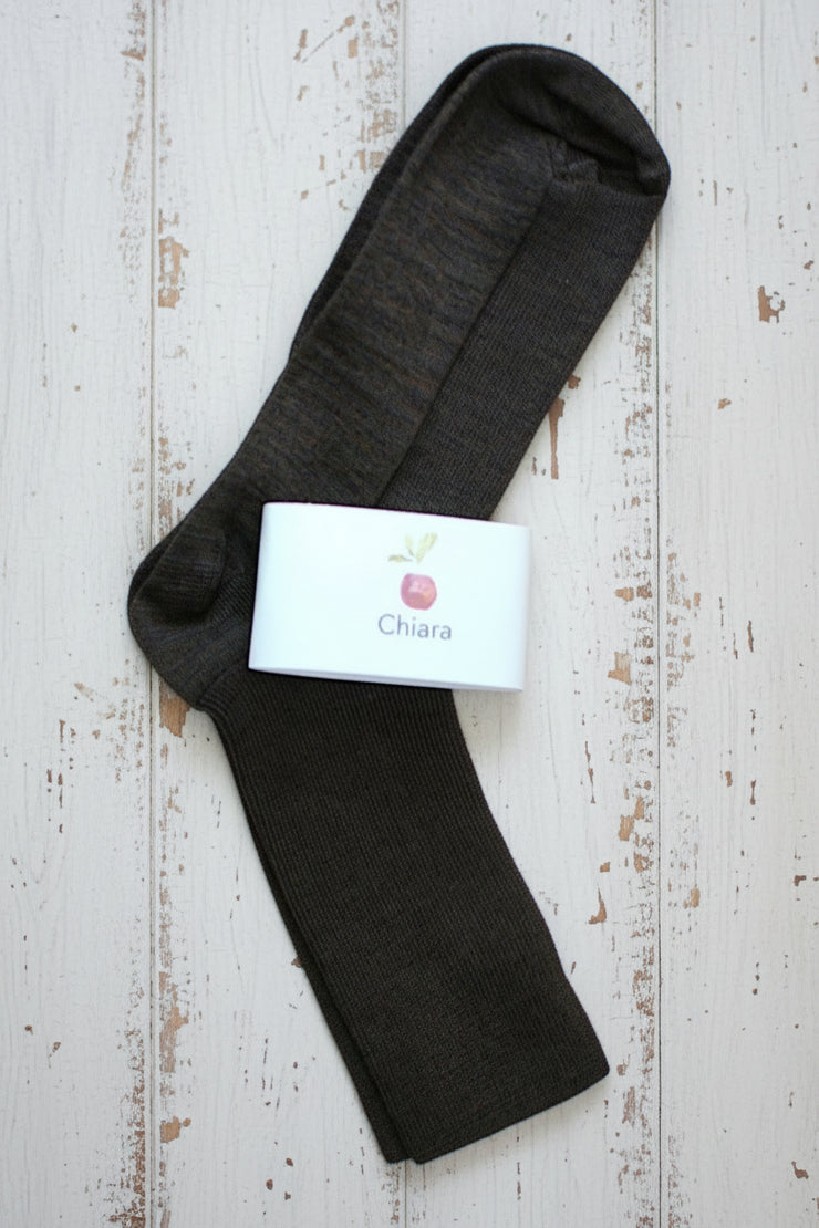 Dark brown ankle sock with a white label on a rustic wooden surface