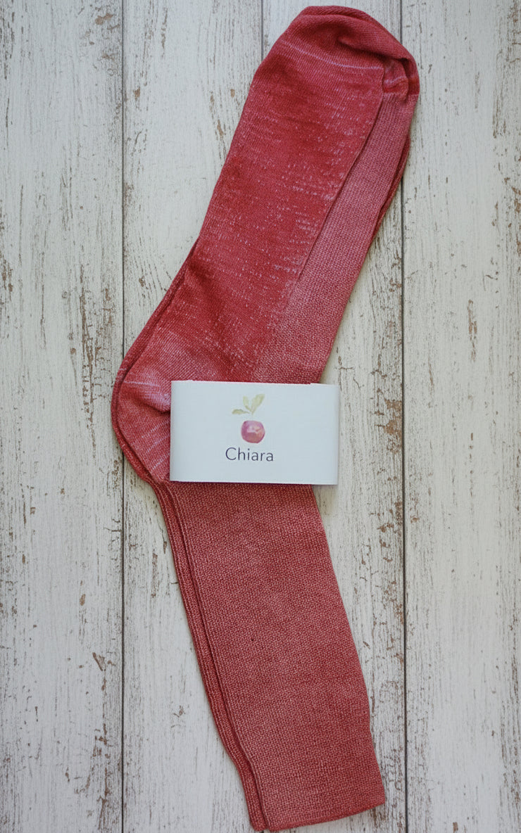 Red sock with a 'Chiara' label on a wooden surface
