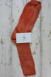 Orange sock with a white label on a wooden surface