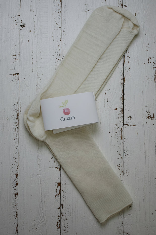 Off white wool socks with a 'Chiara' branded label on a light wooden floor.
