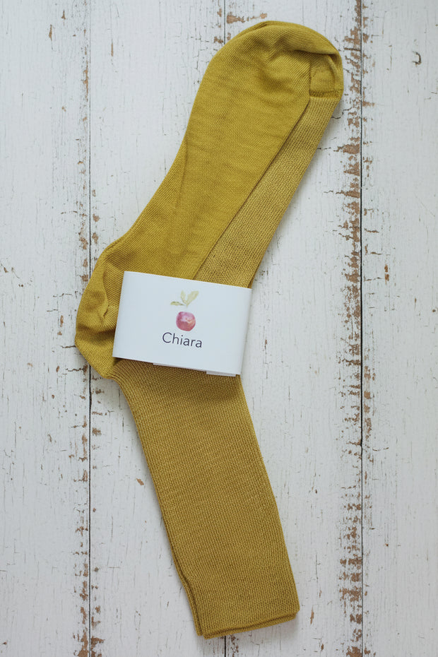 Mustard yellow sock with a white label on a wooden surface