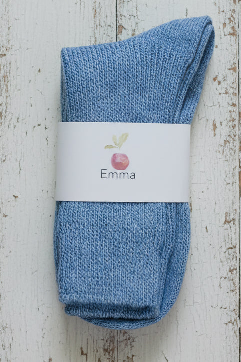 Blue sock with 'Emma' label on a wooden surface