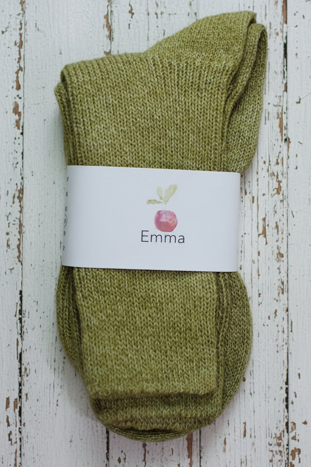 Pair of green socks with a white label on a wooden surface