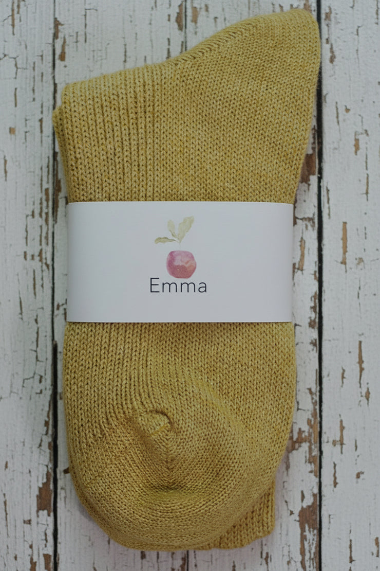 Yellow sock with a white label on a wooden surface