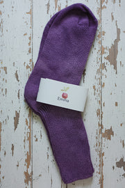 Purple sock with a label on a wooden surface