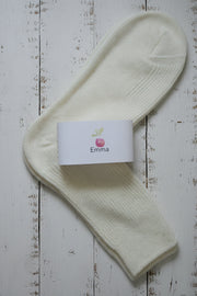 White sock with a 'Emma' brand label on a wooden surface