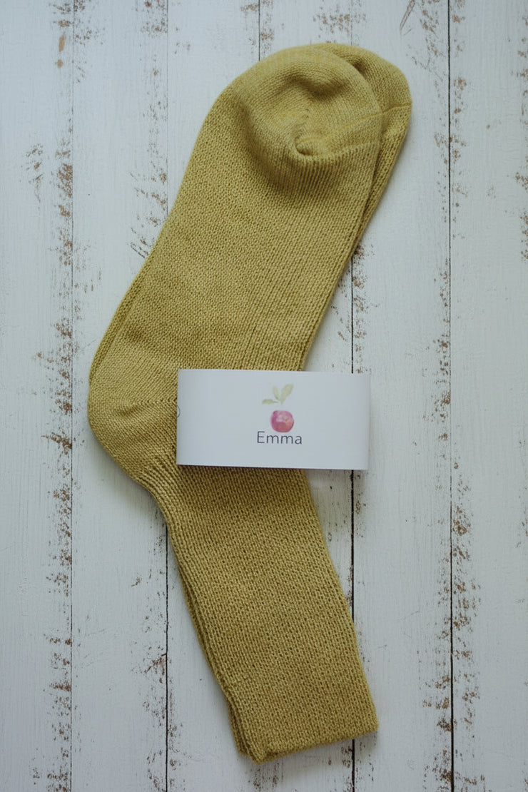Yellow sock with a white label on a wooden surface