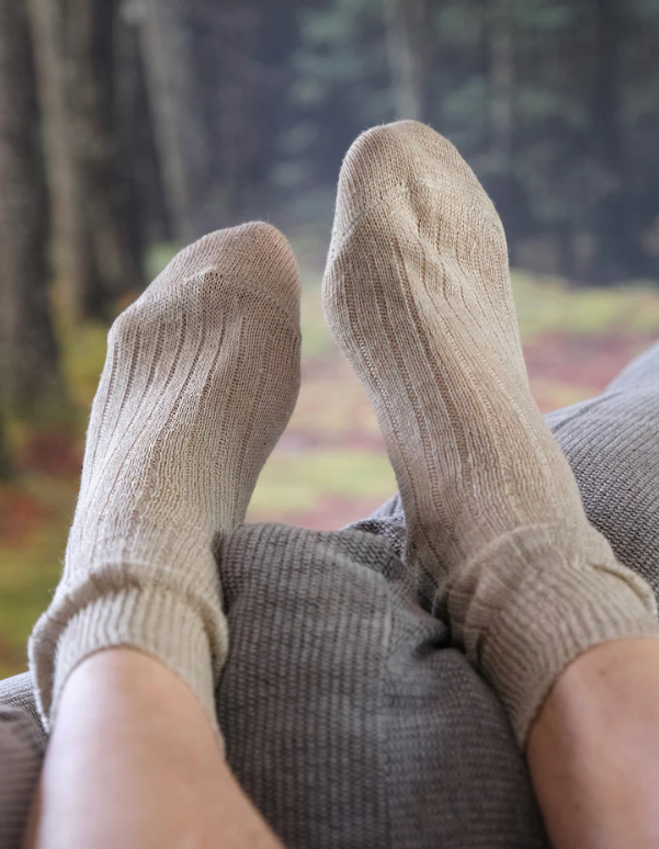 Beige socks worn by a person sitting outdoors with blurred trees in the background