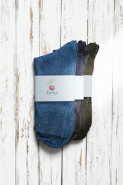 three pairs of socks, one blue, one purple and one brown, with a visible brand label on a wooden surface.