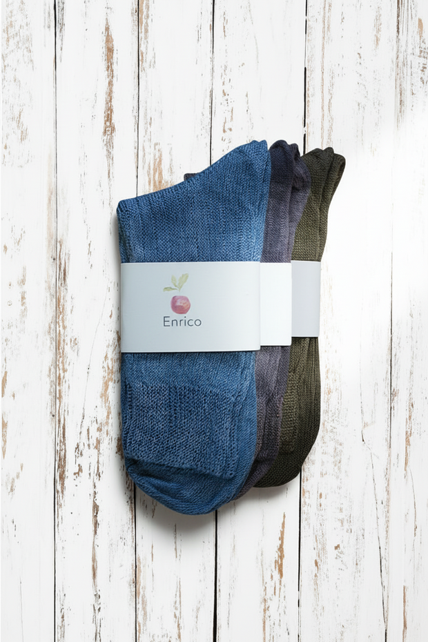 three pairs of socks, one blue, one purple and one brown, with a visible brand label on a wooden surface.