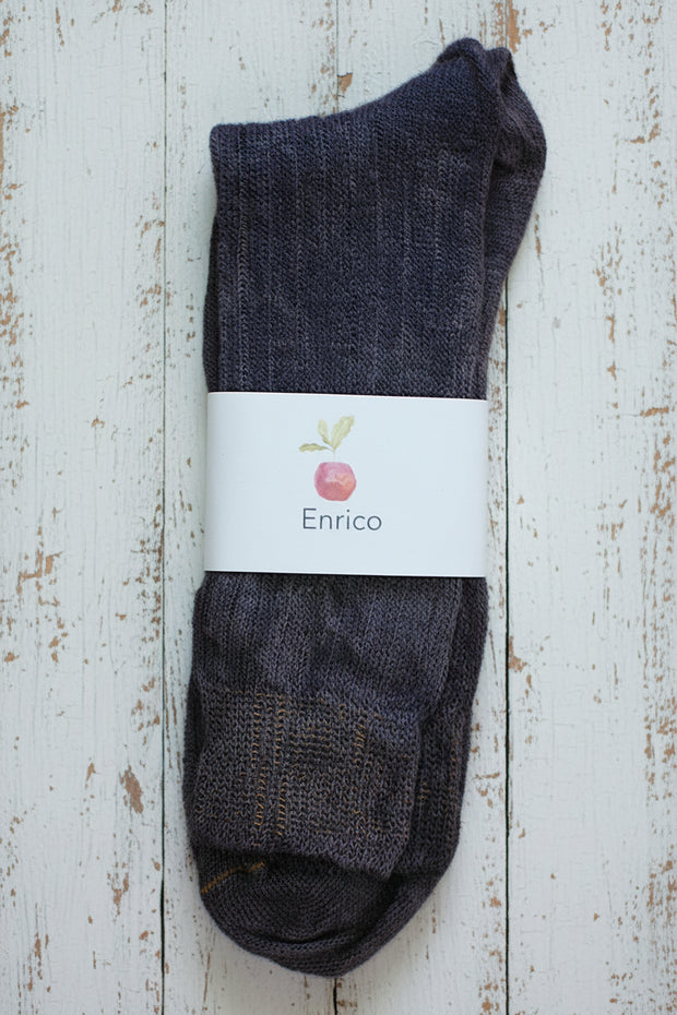 Pair of dark purple socks with a white label on a light wooden surface