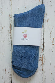 Blue sock with Enrico label on a wooden surface