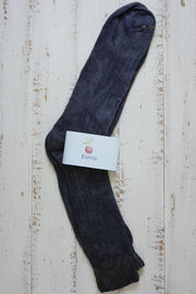Dark purple sock with a visible brand label on a light wooden surface