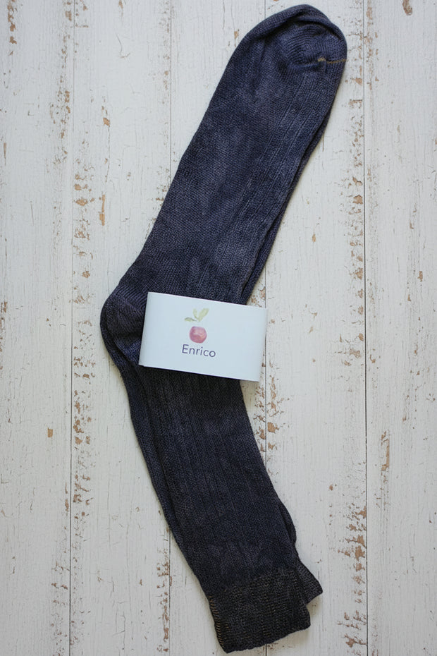 Dark purple sock with a visible brand label on a light wooden surface