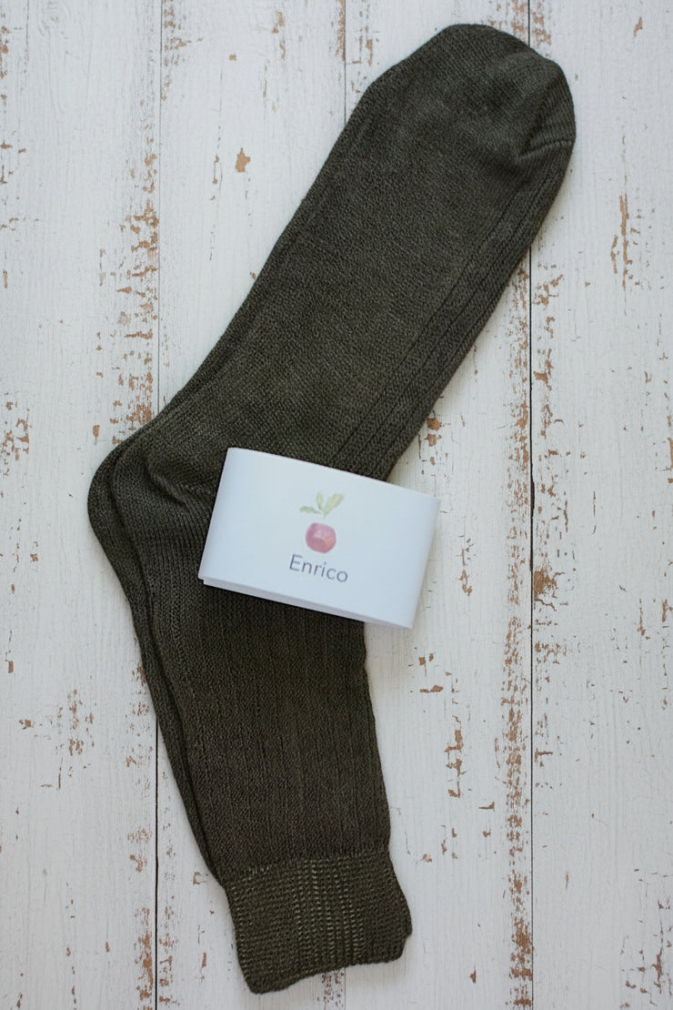 Dark brown sock with a white label on a rustic wooden surface