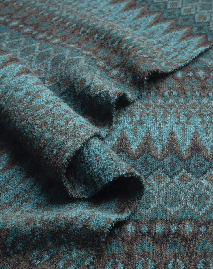 Close-up of textured fabric with a patterned design in teal and brown.