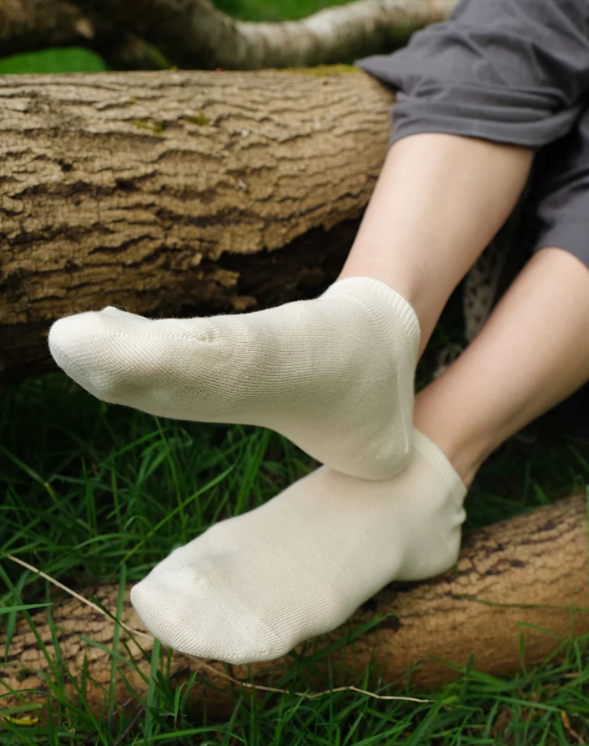 Person wearing white socks sitting on a log in a natural setting