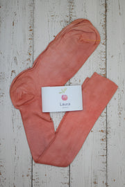 Pair of pink long socks with a 'Laura' brand card on a wooden surface