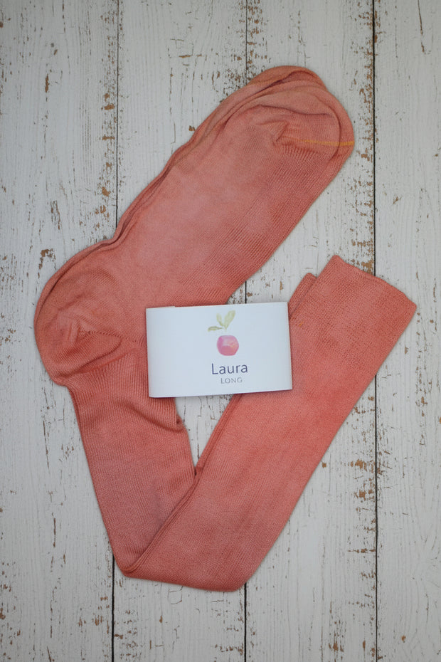 Pair of pink long socks with a 'Laura' brand card on a wooden surface