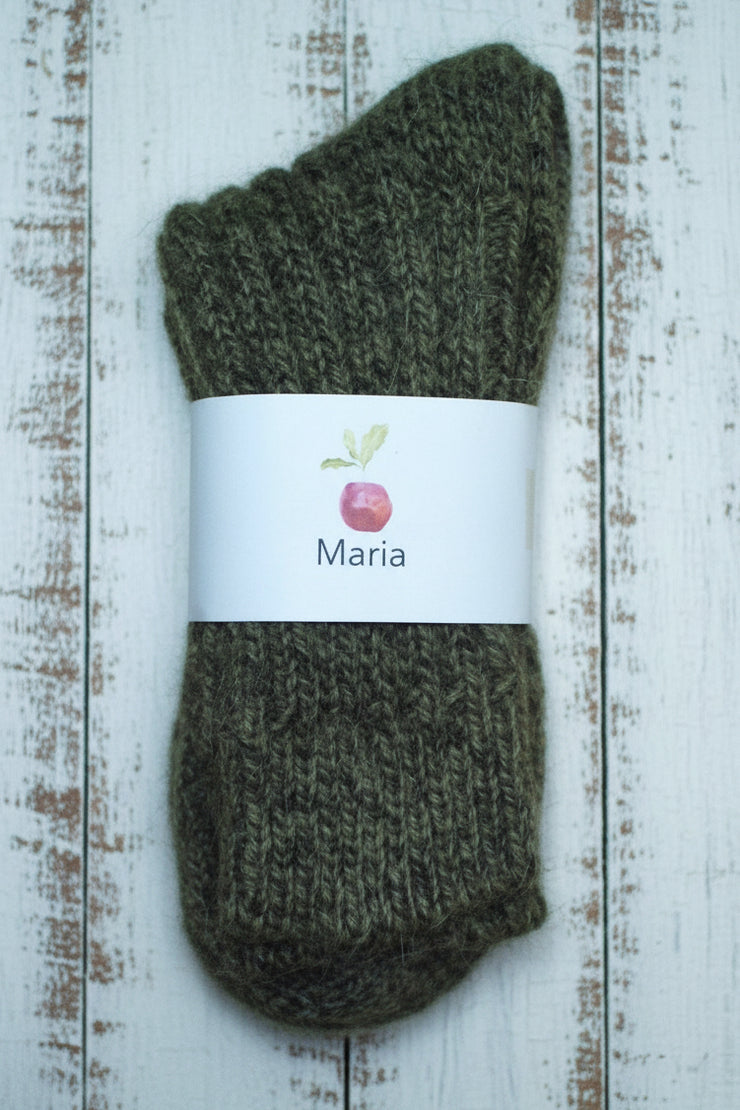 Pair of mottled green socks with a 'Maria' label on a wooden surface