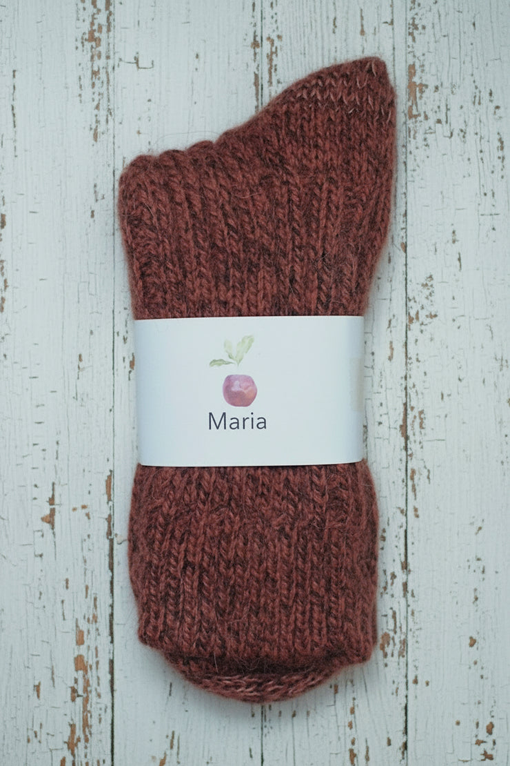 orange mottled knitted sock with a white label on a wooden surface