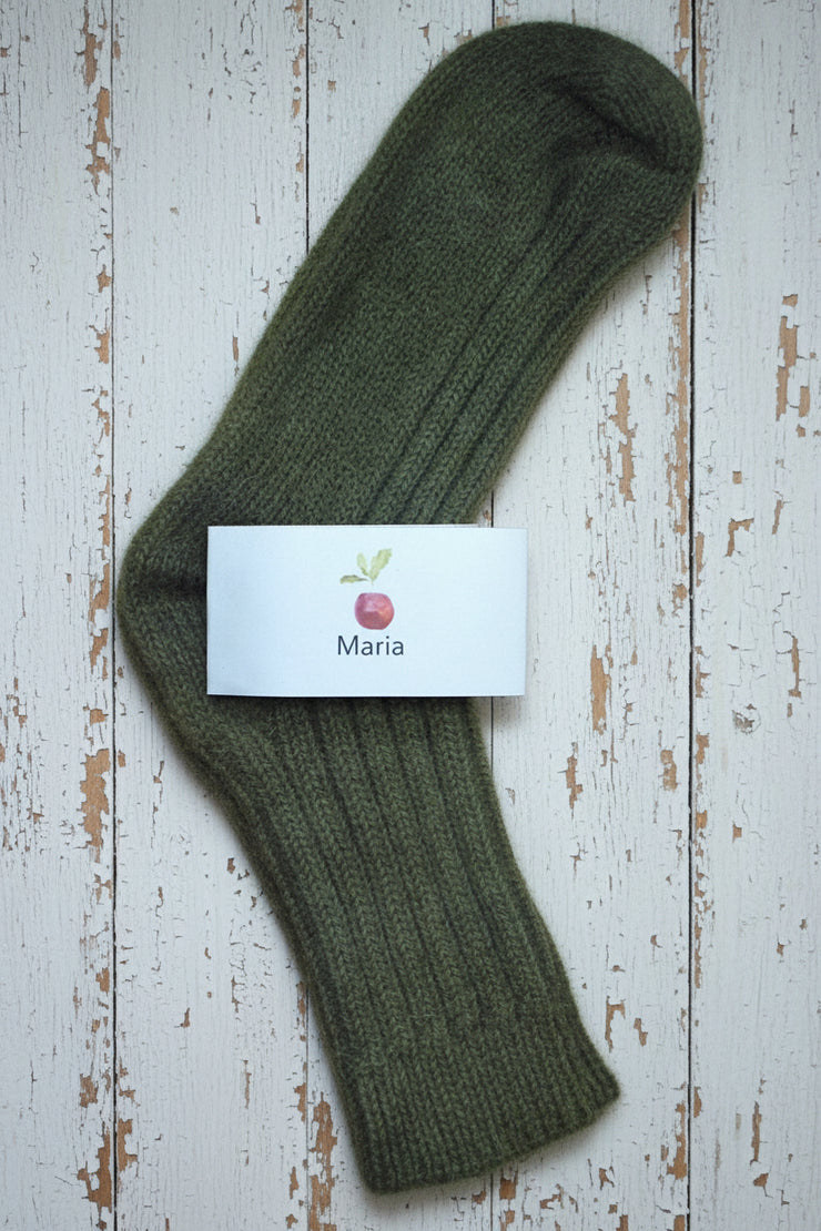 Green sock on a wooden surface with a card labeled 'Maria'.