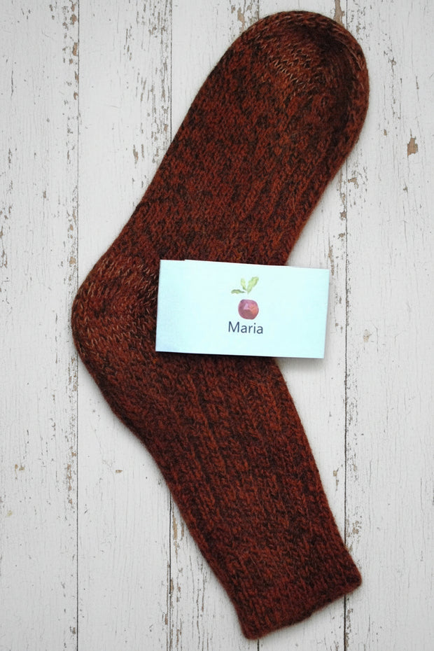 orange wool maria sock with a white label on a wooden surface