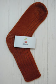 orange sock with a white label on a light wooden surface
