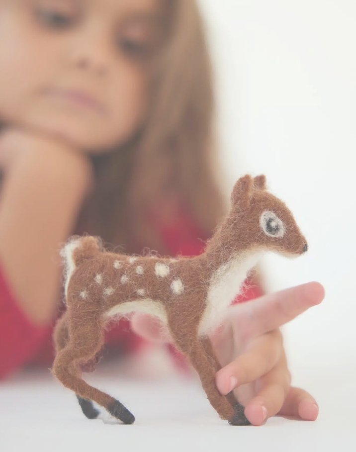 kid playing with felted reindeer